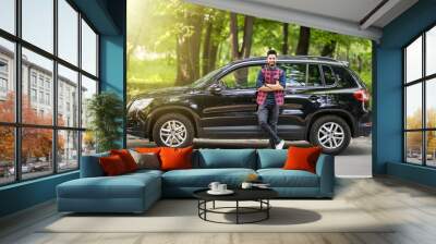 Young handsome indian man standing near his car on the road Wall mural